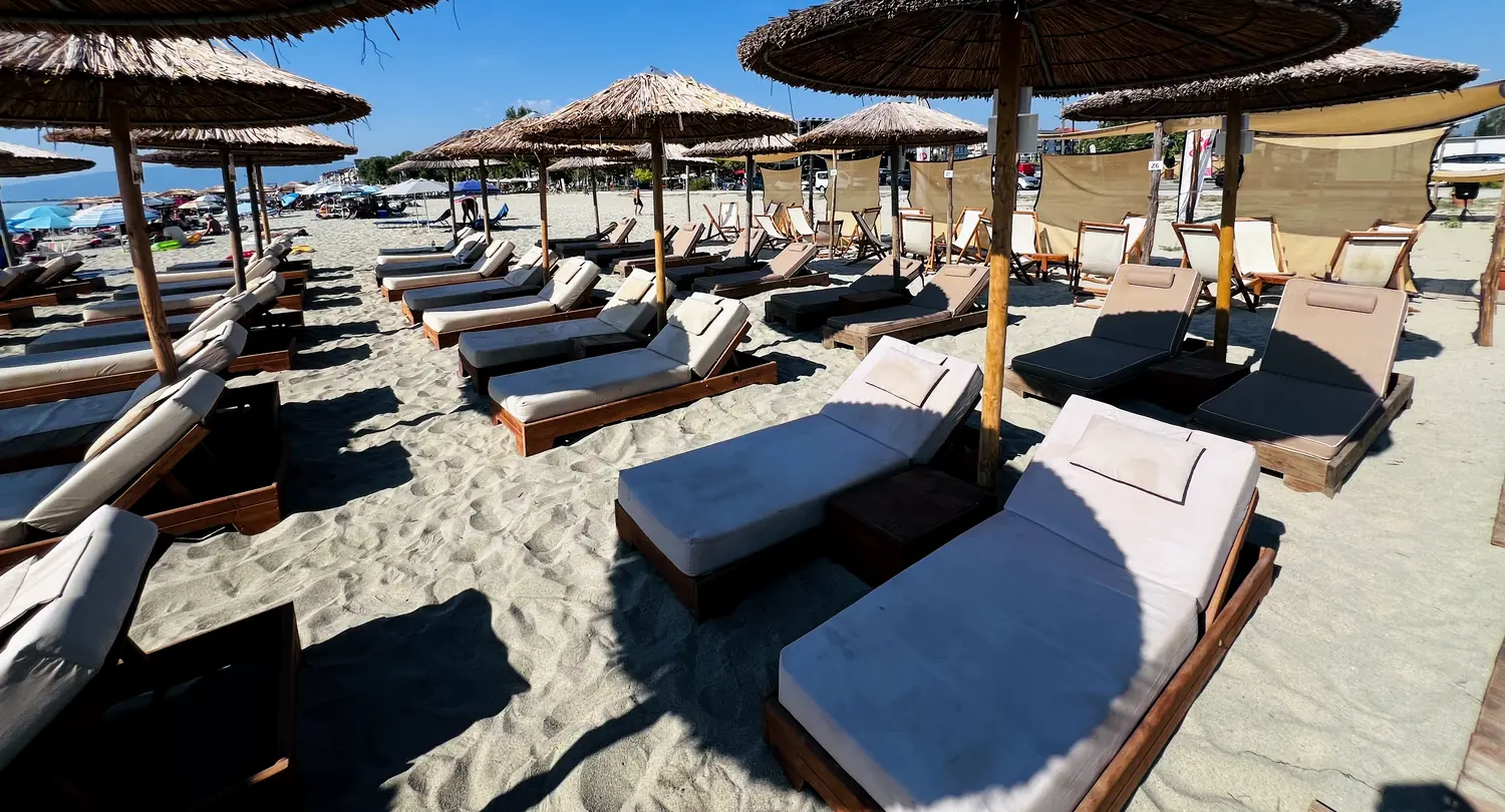 Șezlonguri și umbrare de stuf pe plajă